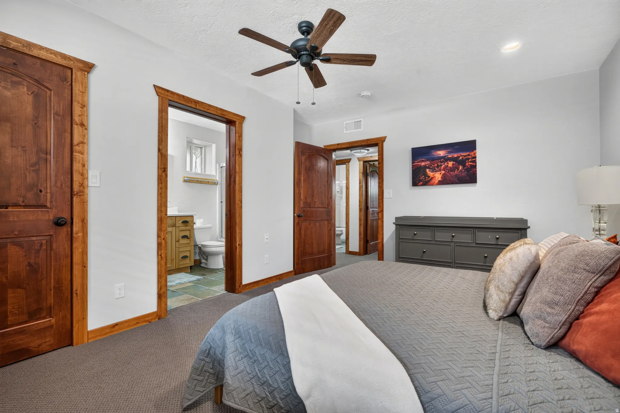 Spacious room featuring wood-finish doors, matching trim, and a ceiling fan