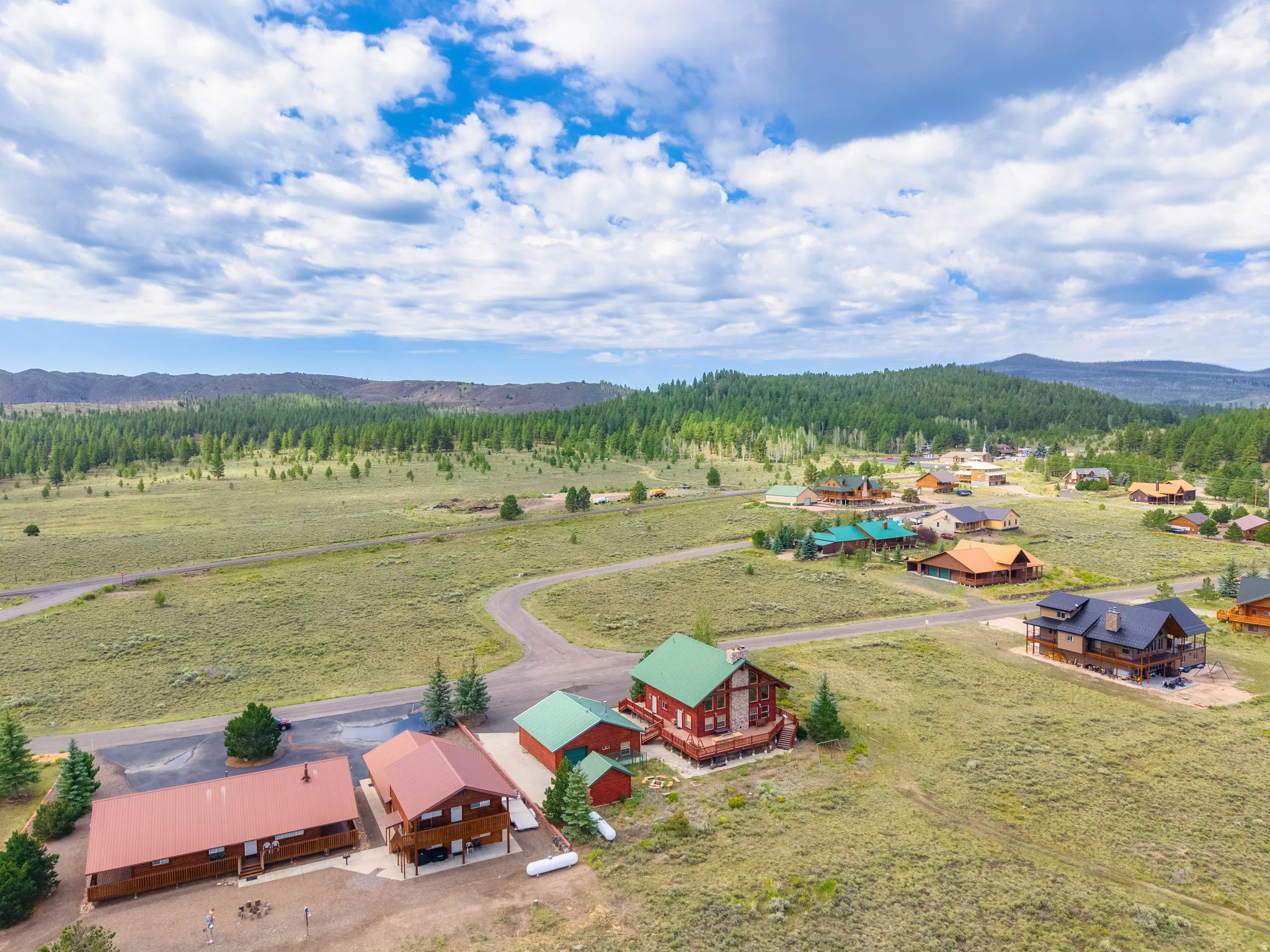 Sprawling rural landscape featuring multiple homes, green meadows, and extensive tree cover