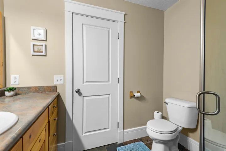 Well-appointed bathroom featuring warm wood-finish cabinetry with an undermount sink, gray-toned countertop, and chrome hardware