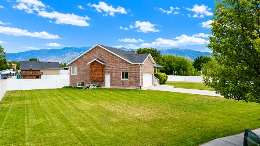 Brick exterior residence featuring an attached garage, white fencing, and a concrete driveway