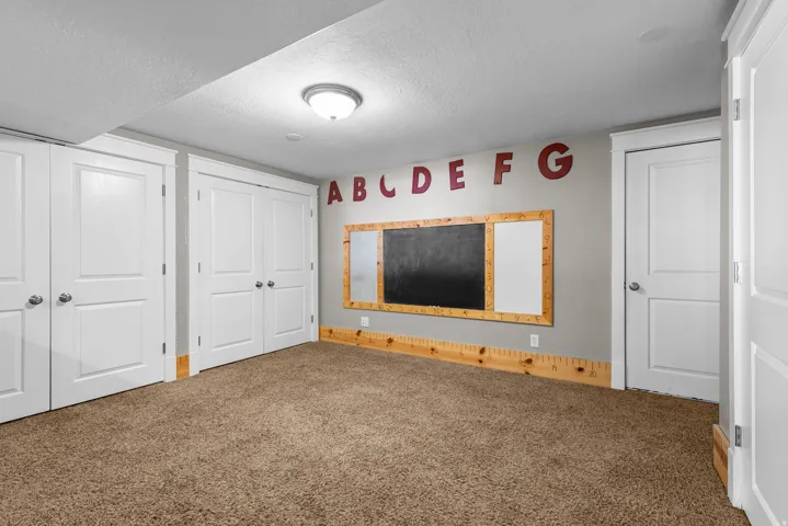 Spacious recreation room featuring carpet flooring, recessed ceiling lighting, and multiple white six-panel closet doors