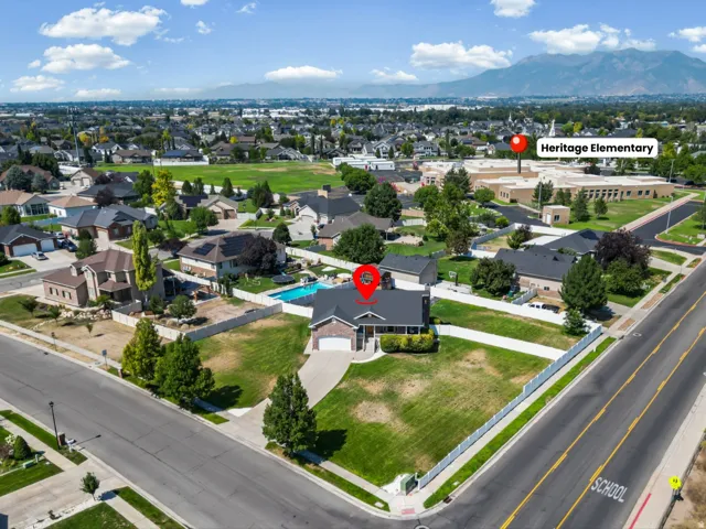 Residential property featuring a large front yard, an attached garage, a paved driveway, and a fenced backyard