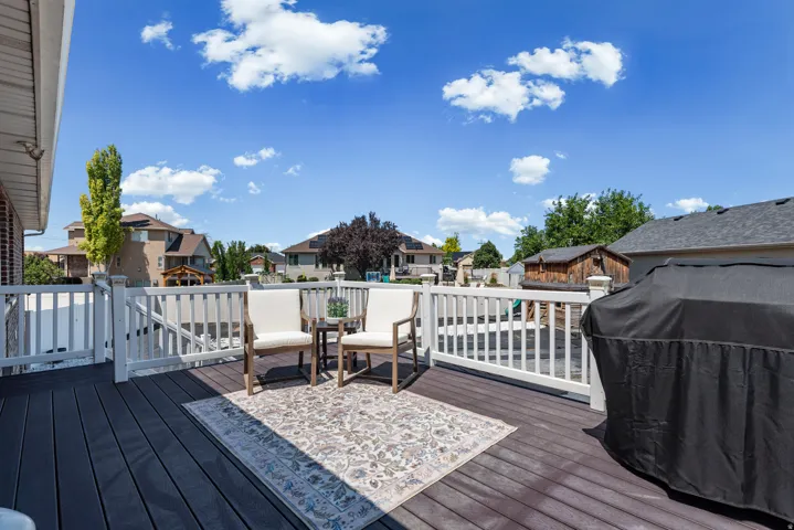 Expansive composite deck featuring dark wood-finish decking, white aluminum railings, and defined entertaining spaces