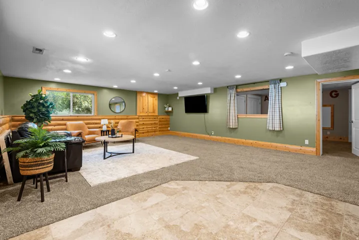 Spacious lower-level area featuring recessed lighting, a combination of carpet and tile flooring, and light green wall paint