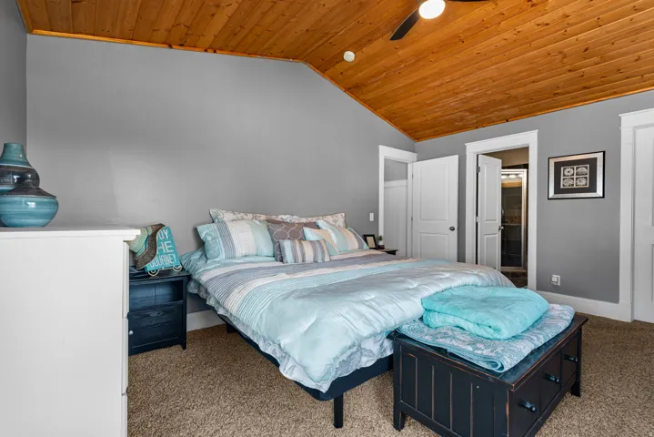 Spacious bedroom featuring a wood-finish ceiling, gray walls, and carpeted flooring