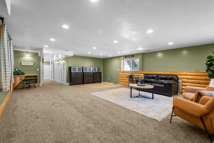 Expansive lower-level space featuring green walls, recessed lighting, and carpet flooring