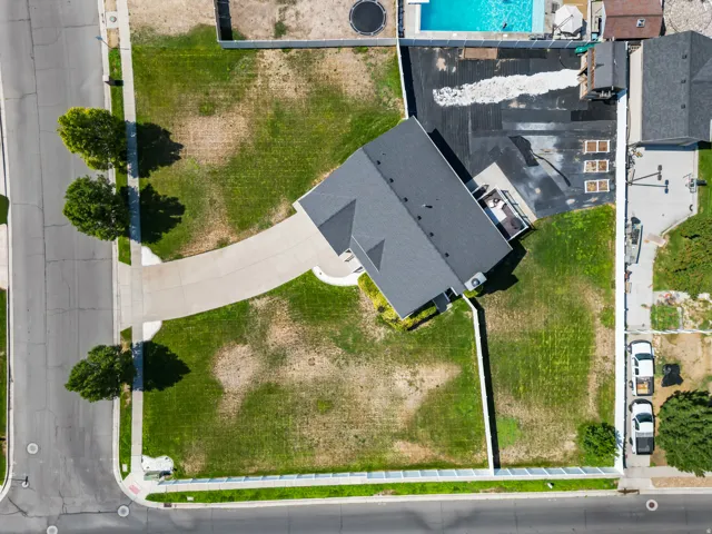 Aerial view showcasing a contemporary residence with a charcoal gray architectural roof, situated on a generous lot with mature landscaping