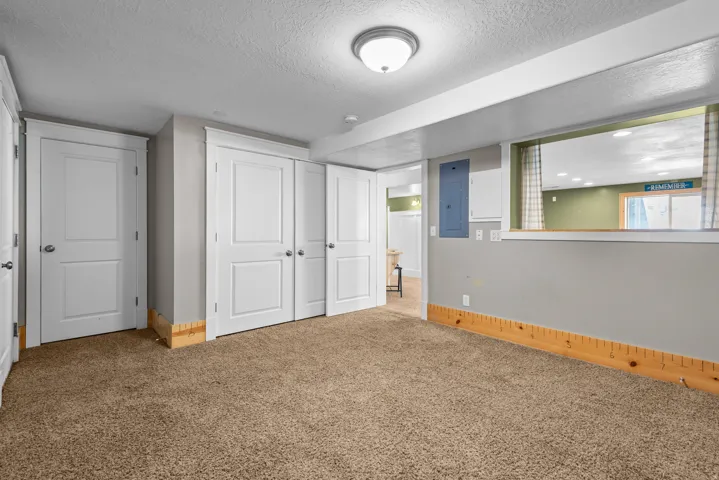 Spacious recreation room featuring neutral gray walls, abundant natural light from recessed ceiling fixtures, and durable carpet flooring