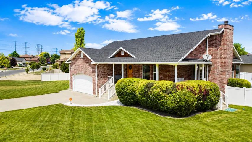 Brick ranch-style residence featuring a prominent front porch with white columns, an attached garage, and a dark shingle roof