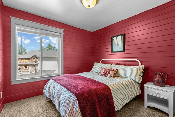 Charming bedroom featuring bold red shiplap walls, large multi-pane windows with white trim.