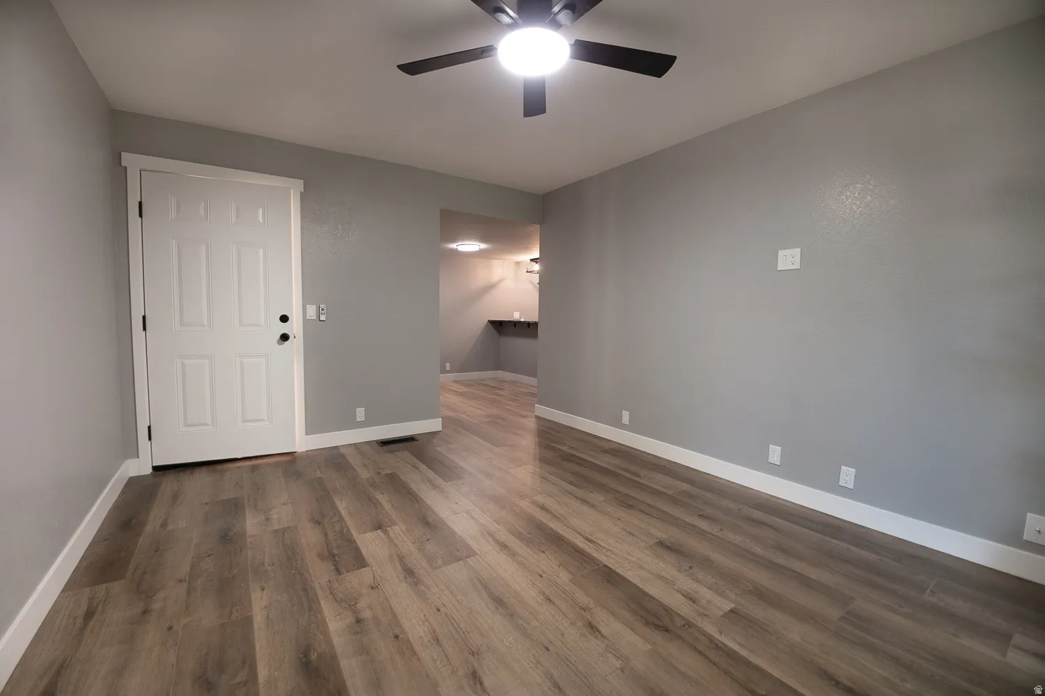 Spacious room featuring wood-finish flooring, light gray walls, and white baseboards