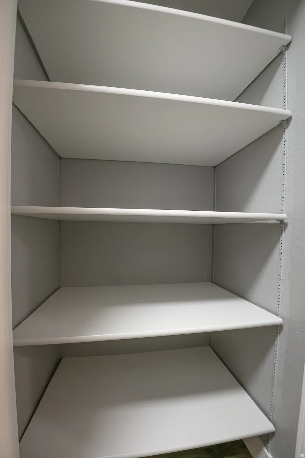 Built-in shelving unit featuring multiple white shelves, gray interior walls, and adjustable shelf supports