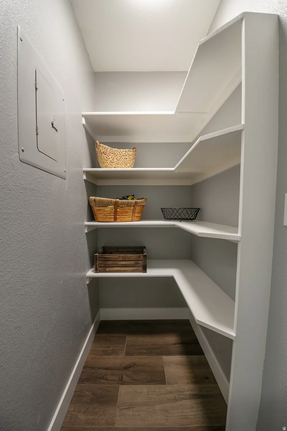 Built-in white shelving system with wood-finish flooring and light gray walls