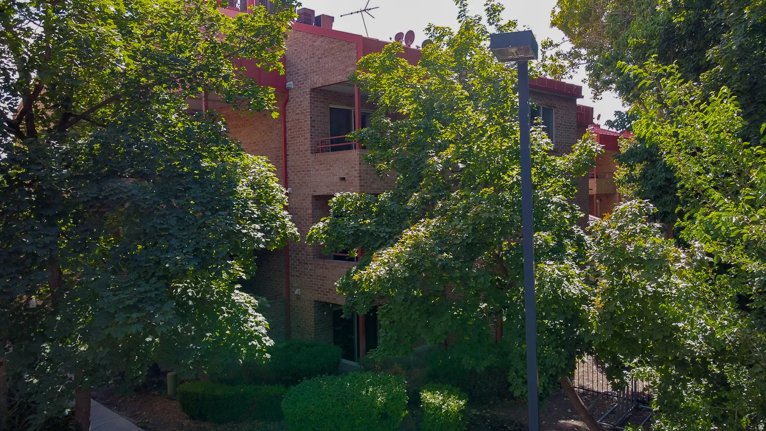 Brick exterior featuring multiple levels, balconies with metal railings, and a red roofline