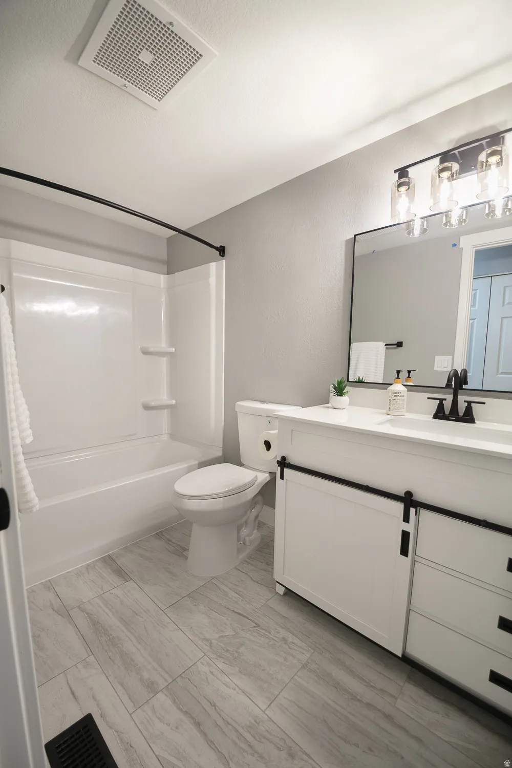 Bathroom featuring a white vanity with a white countertop and black hardware