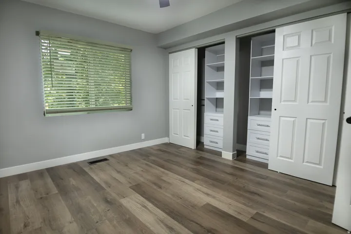 Spacious room featuring wood-finish flooring, light gray wall tones, and white baseboards