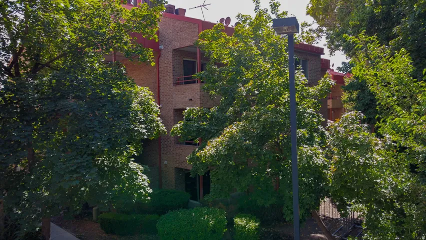 Brick exterior featuring multiple levels, balconies with metal railings, and a red roofline