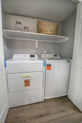 Dedicated laundry area featuring wood-finish flooring, a white floating shelf, and neutral gray wall paint