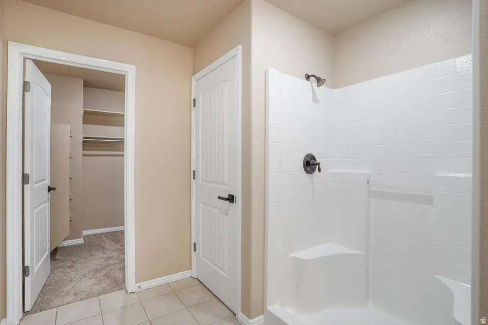 Shower enclosure featuring a built-in bench, dark bronze fixtures, and white subway tile-patterned wall panels