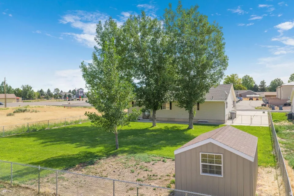Spacious backyard featuring a manicured lawn, established trees, and a functional storage shed