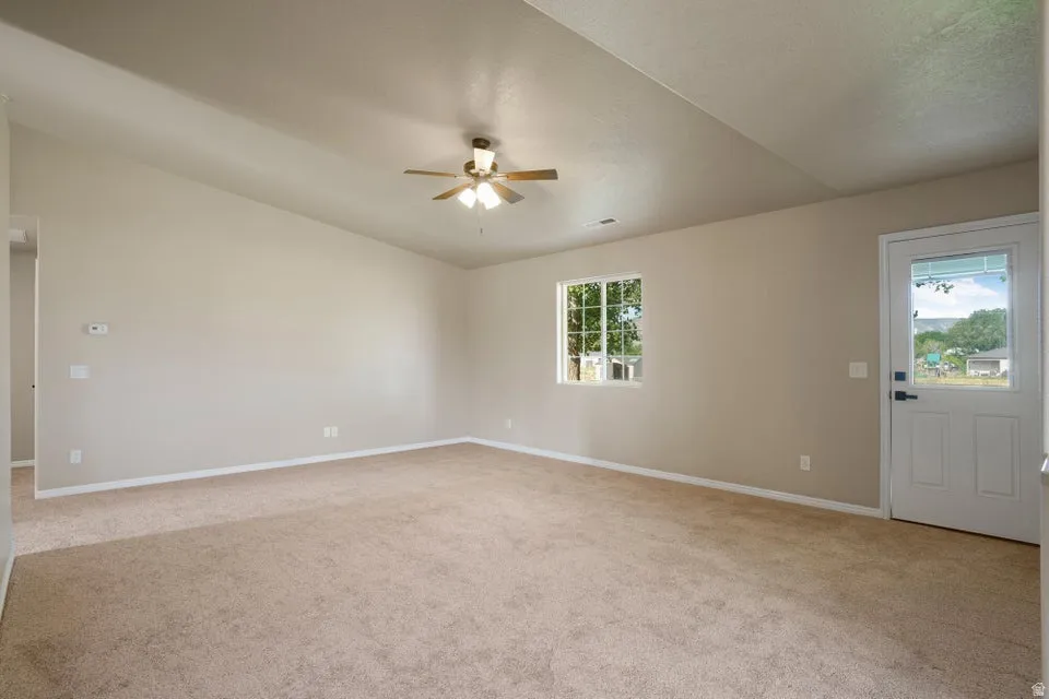 Spacious room featuring vaulted ceilings, light neutral wall tones, and plush carpeting
