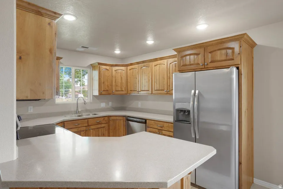 Kitchen featuring light wood cabinetry, light-toned countertops, stainless steel appliances, and recessed lighting