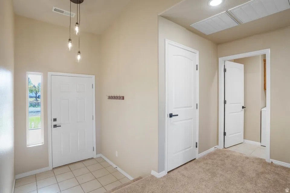 Entryway featuring a white paneled door with matte black hardware, sidelight window, and a contemporary pendant light fixture