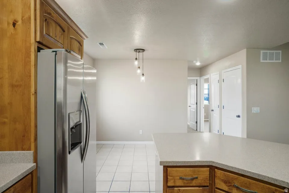 Kitchen with wood cabinetry, stainless steel refrigerator, and light-toned countertops
