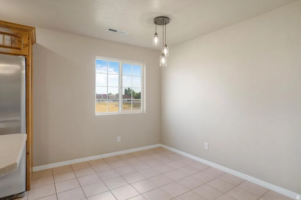 Dining area featuring a modern three-light pendant fixture, a large window with grid pattern, and light-toned tile flooring
