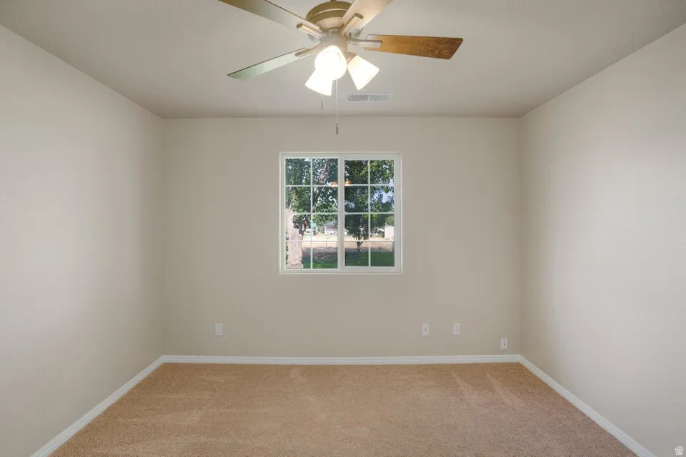 Neutral tone walls with white trim, a single window with grid panes, and a ceiling fan with light fixture
