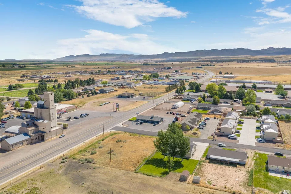 Expansive aerial view of a rural town featuring a prominent multi-story industrial building, residential properties, and commercial structures