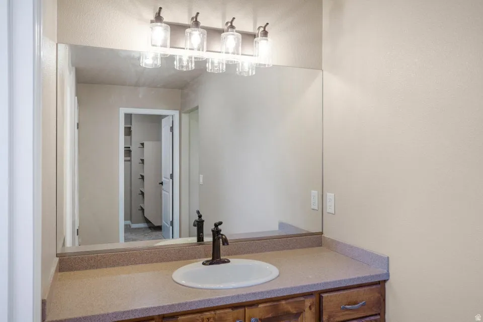 Single vanity with an oval sink, bronze-finish faucet, and coordinating light fixture