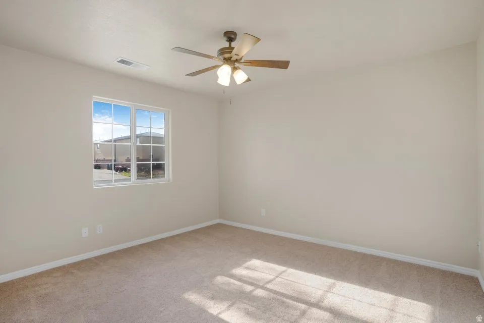 Neutral-toned carpet flooring and walls, featuring a multi-pane window with white trim