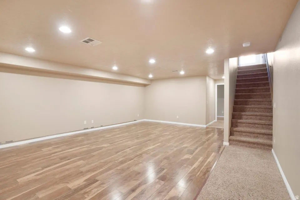 Spacious room featuring wood-finish flooring, recessed lighting, and neutral-toned walls