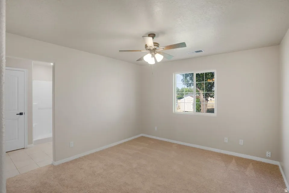 Carpeted interior room featuring a ceiling fan with integrated lighting, a single window, and neutral wall tones