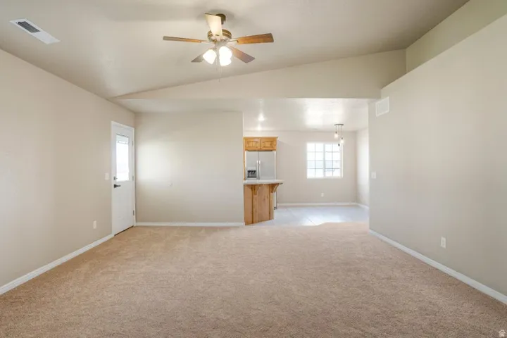 Spacious living area featuring neutral carpeting and vaulted ceilings