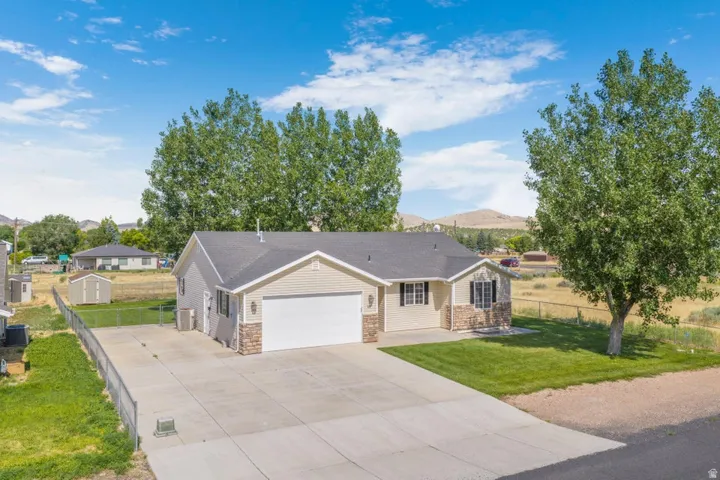 Ranch-style residence featuring a two-car garage, stone veneer accents, and light-colored siding