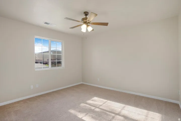 Neutral-toned carpet flooring and walls, featuring a multi-pane window with white trim