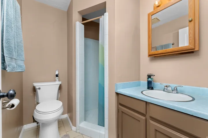 Bathroom featuring a single vanity with a light blue countertop, an oval undermount sink, and a framed mirror cabinet