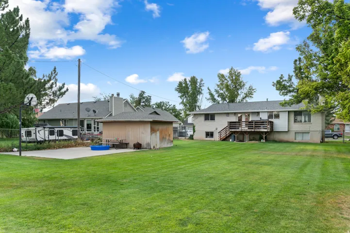 Expansive green lawn with a two-story residence featuring a ground-level deck