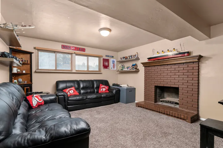 Living space featuring a brick fireplace with a wood mantle, neutral wall paint, and a textured carpeted floor