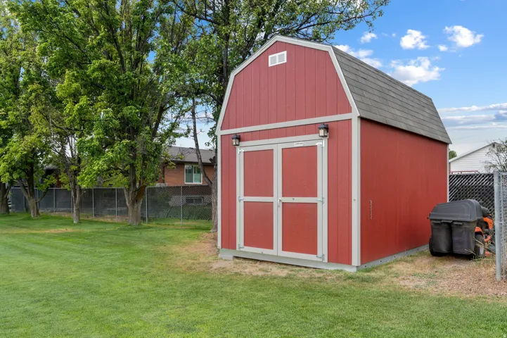 Red barn-style shed featuring a gambrel roof and double entry doors