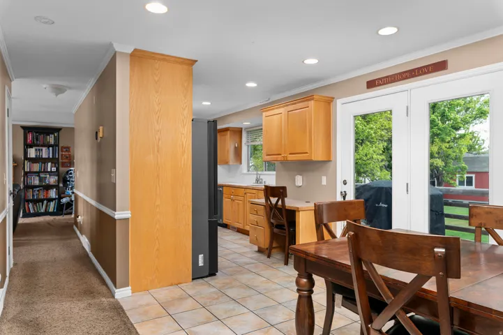 Kitchen featuring tile flooring, light wood-finish cabinetry, recessed ceiling lighting, and a white tile backsplash