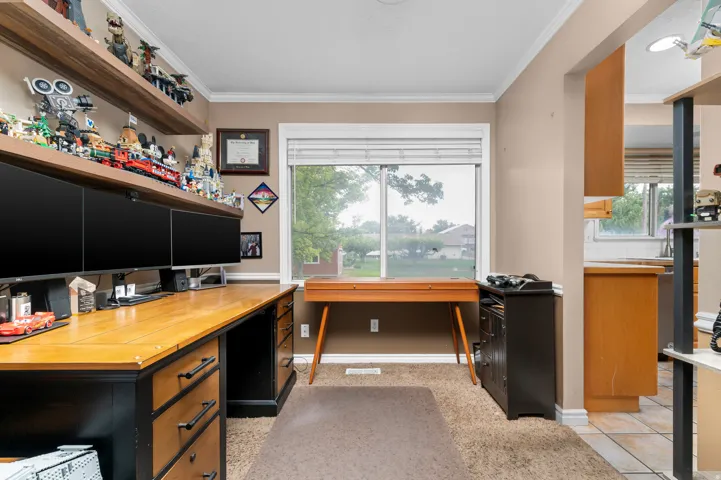 Dedicated workspace featuring built-in wood-finish shelving, a large picture window, and carpet flooring