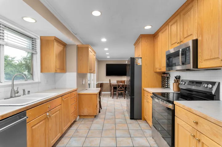 Galley kitchen featuring light wood cabinetry, a double basin sink with a brushed nickel faucet, and a white subway tile backsplash