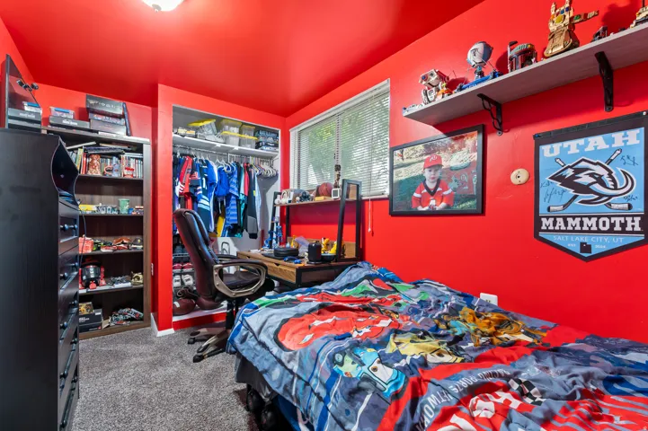 Room featuring red painted walls and ceiling, a built-in closet with shelving and hanging rod, a window with blinds, and carpeting