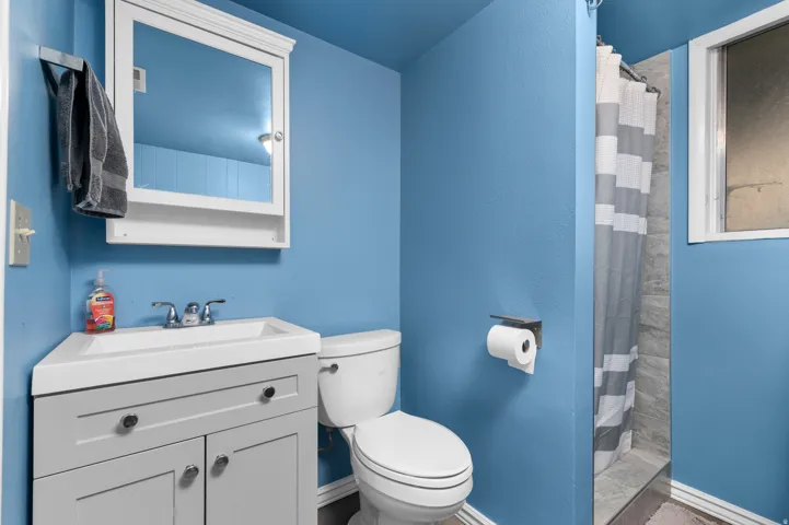 Bathroom featuring a gray vanity with an integrated sink, polished chrome faucet, and a white medicine cabinet