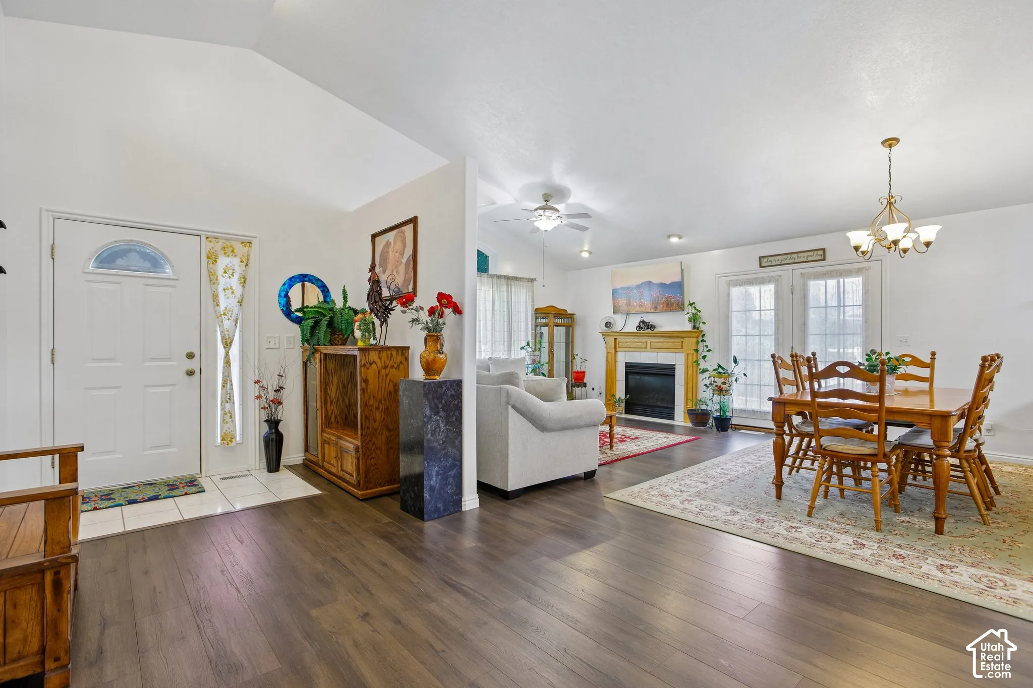 Open-concept living area featuring wood-finish flooring, vaulted ceilings, and a fireplace with a wood mantle