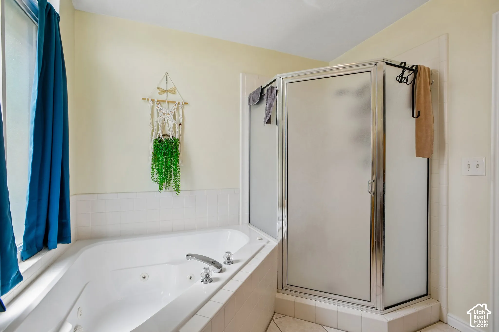 Corner jetted soaking tub with chrome fixtures, surrounded by white tile