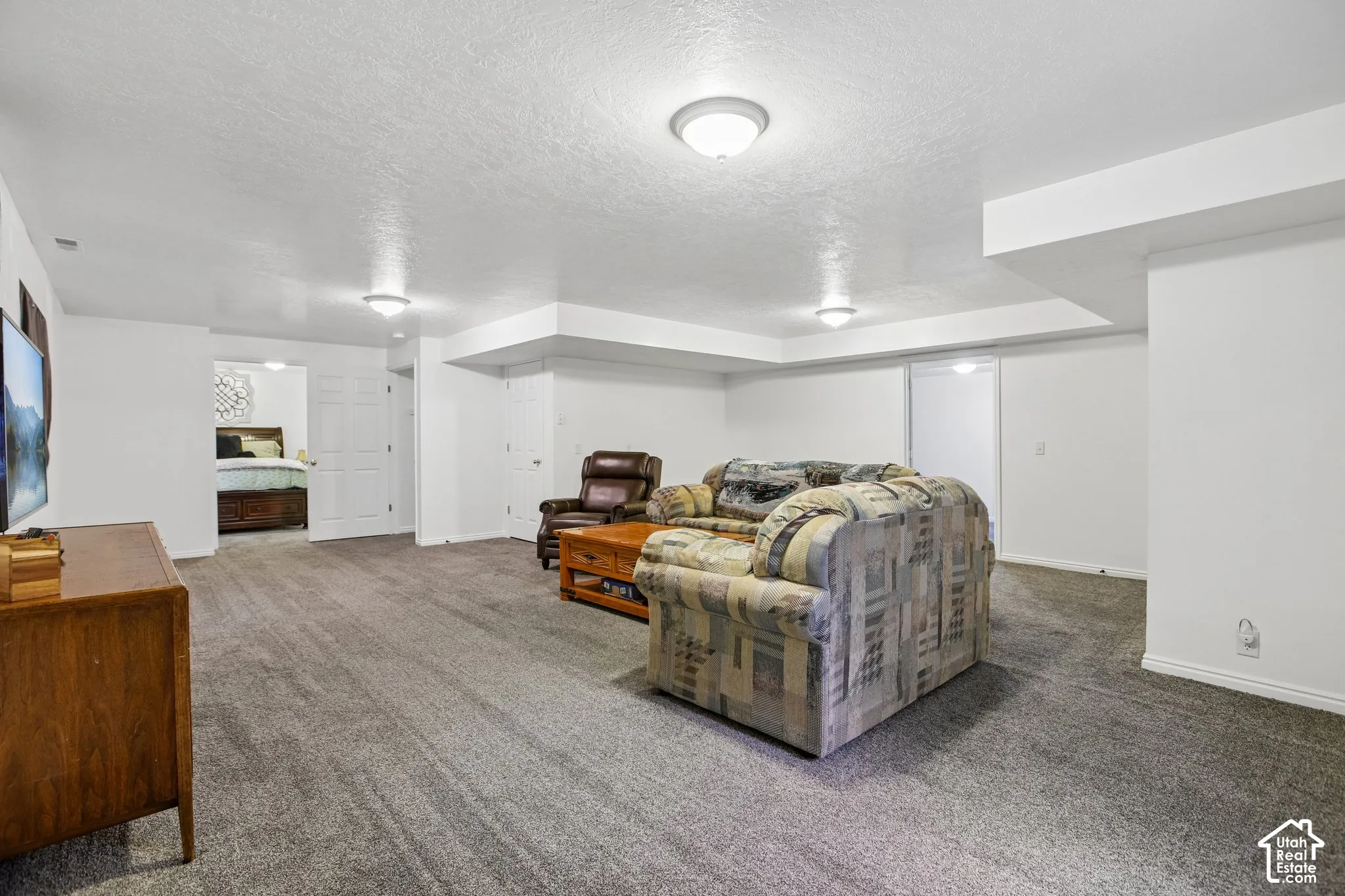 Spacious recreation room featuring neutral carpeting, recessed ceiling lighting, and white baseboards